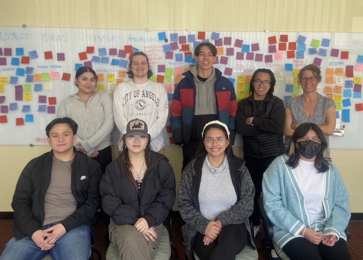 accelerate program students pose in front of a white board covered in sticky notes