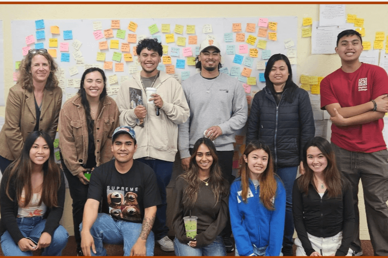 Accelerate scholars cohort 2024 pose in front of idea board covered in sticky notes